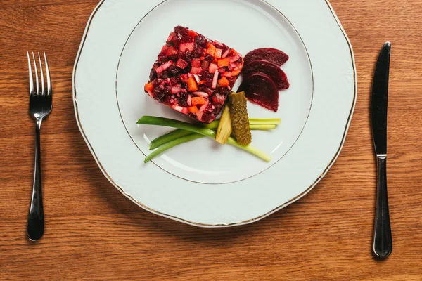 Vinaigrette salade posée sur une assiette sur une table en bois avec fourchette et couteau — Photo de stock