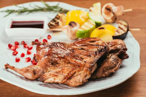 Vue rapprochée des légumes grillés dans une assiette avec du poulet frit sur une table en bois — Photo de stock