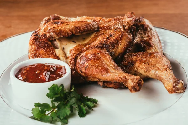 Aves de corral horneadas que ponen en plato con salsa y hierbas - foto de stock