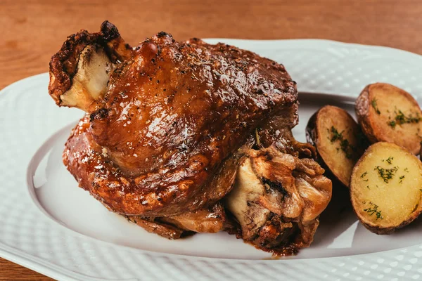 Close-up grilled meat on bone with potatoes on white plate — Stock Photo