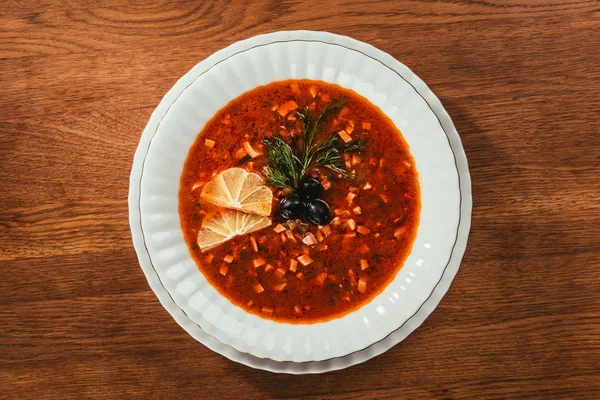 Sopa com fatias de laranja e azeitonas com ervas em placa sobre a superfície de madeira — Fotografia de Stock