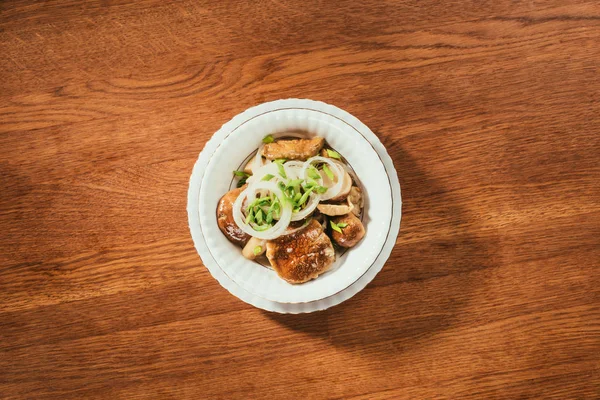 Top view of pickled mushrooms with onion on white plate on wooden table — Stock Photo