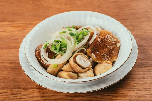 Marinated mushrooms with fresh onion rings on plate over wooden surface — Stock Photo