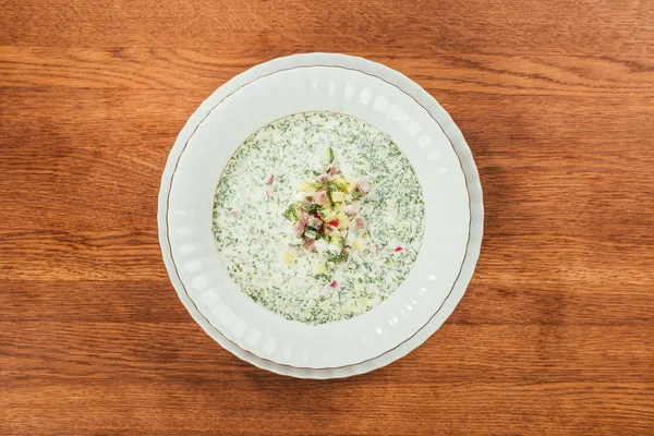 Sopa de okroshka com ervas em placa branca sobre a superfície de madeira — Fotografia de Stock