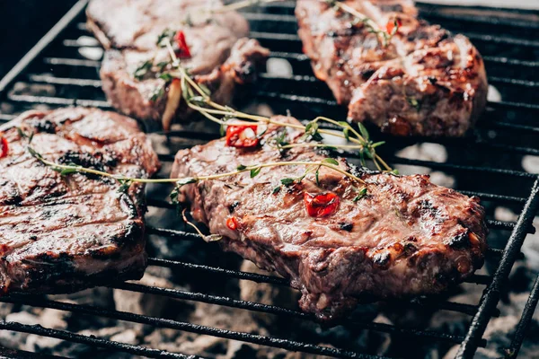 Close-up view of delicious juicy meat with spices preparing on grill — Stock Photo