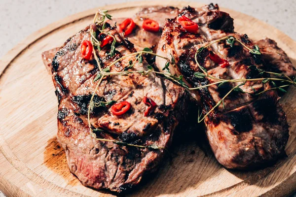 Vista de cerca de la deliciosa carne jugosa a la parrilla con especias en tablero de madera - foto de stock