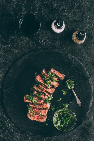Вид зверху на гастрономічне нарізане м'ясо на грилі з соусом та спеціями на чорному — стокове фото