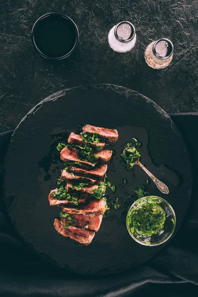 Vista dall'alto di deliziose fette di carne alla griglia con salsa e spezie su nero — Foto stock