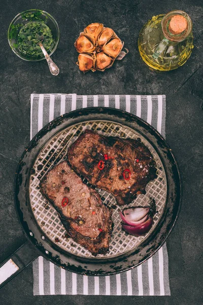 Top view of delicious roasted meat on frying pan with spices on black — Stock Photo