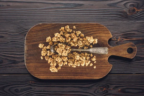 Vista superior de granola crocante e colher em tábua de madeira na mesa — Fotografia de Stock
