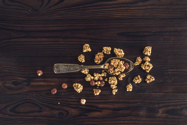 Top view of crunchy granola and hazelnuts on spoon on wooden table — Stock Photo