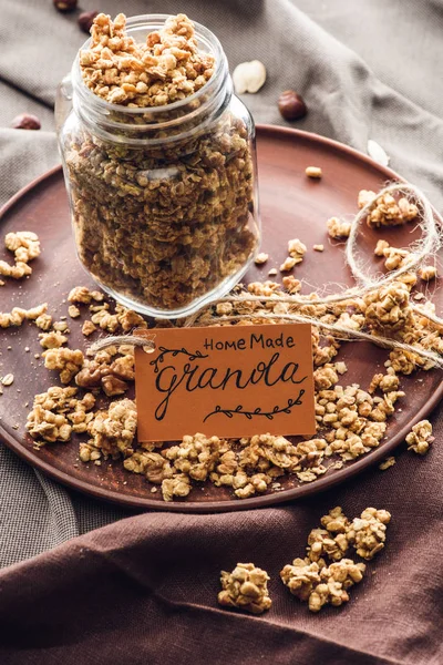 Granola appétissant fait maison en pot en verre avec étiquette sur le plateau — Photo de stock