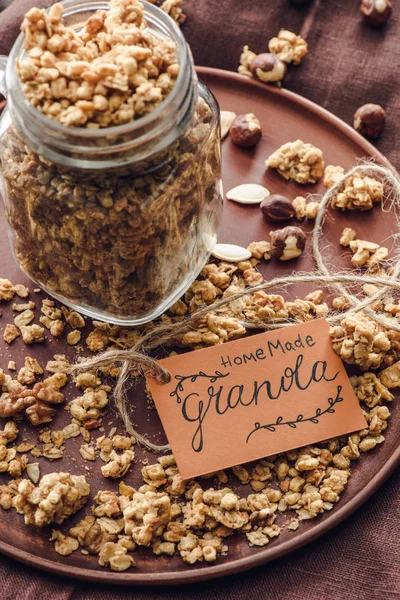 Vue aérienne de granola savoureux maison dans un bocal en verre avec étiquette sur le plateau — Photo de stock