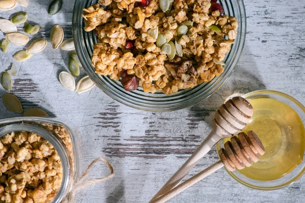 Vista dall'alto di granola e miele con bastoncini su superficie di legno — Foto stock