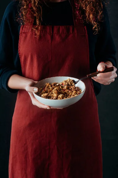 Cropped image of female cook holding bowl with granola and spoon — Stock Photo