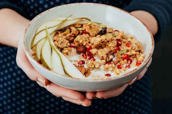 Imagen recortada de cocinera hembra sosteniendo tazón con granola con frutas y frutos secos - foto de stock