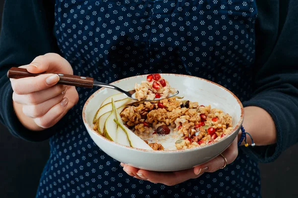 Imagen recortada de cocinera hembra sosteniendo tazón con granola y cuchara en las manos - foto de stock