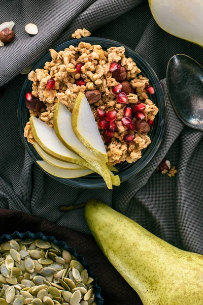 Top view of crunchy granola with pears and pomegranate seeds on table — Stock Photo