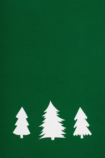 Vista superior de los árboles de navidad de papel decorativo sobre fondo verde con espacio para copiar - foto de stock