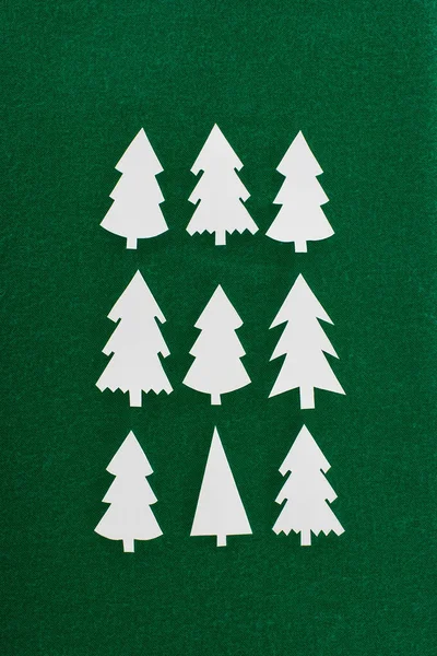 Top view of decorative paper christmas trees on green background — Stock Photo