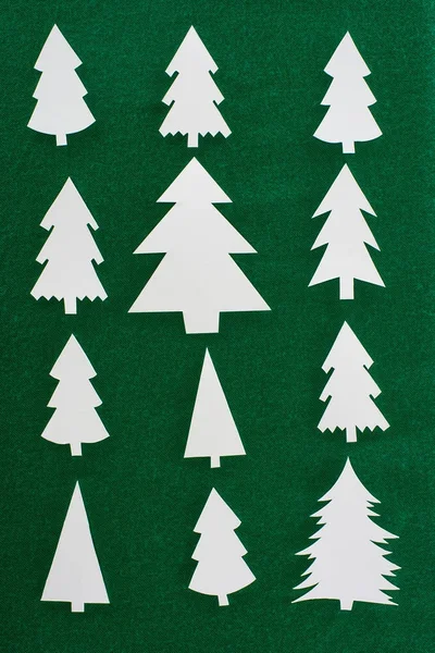Top view of white paper christmas trees on green background — Stock Photo
