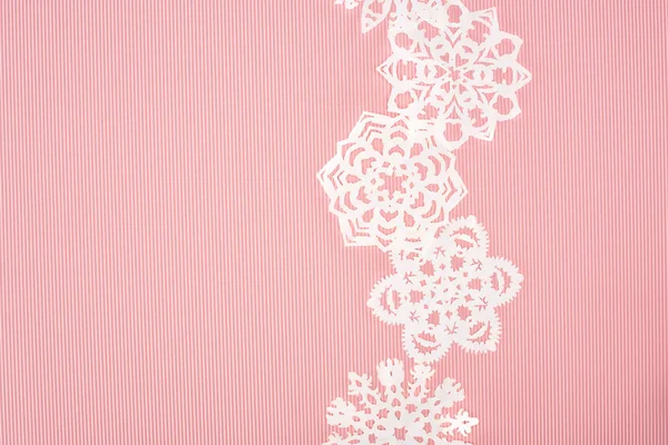 Christmas background with decorative paper snowflakes on pink — Stock Photo