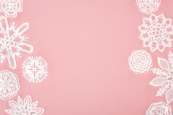 Fond de Noël avec des flocons de neige en papier sur rose — Photo de stock