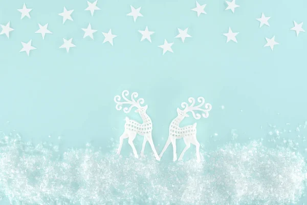 Fond de Noël avec neige décorative, étoiles et cerfs en papier, isolé sur bleu clair — Photo de stock
