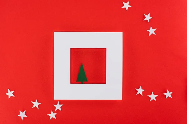 Albero di Natale in cornice bianca con stelle intorno, isolato su rosso — Foto stock