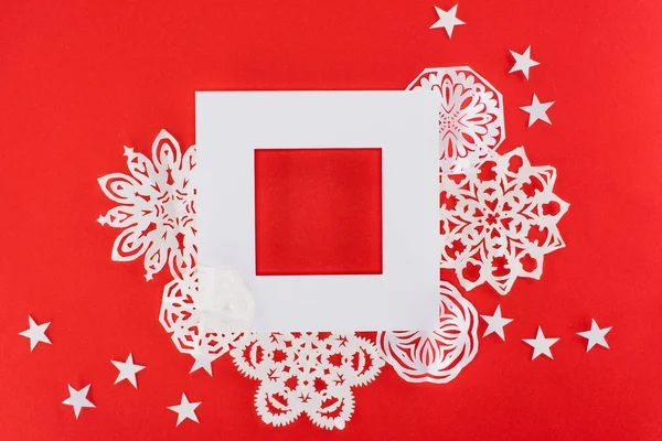 Marco de Navidad blanco con estrellas y copos de nieve de papel alrededor, aislado en rojo - foto de stock