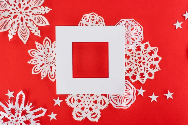 Marco de Navidad blanco con estrellas y copos de nieve de papel alrededor, aislado en rojo - foto de stock