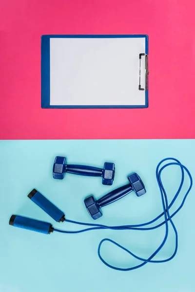 Dumbbells esportes, prancheta e pular corda isolada em rosa e azul — Fotografia de Stock