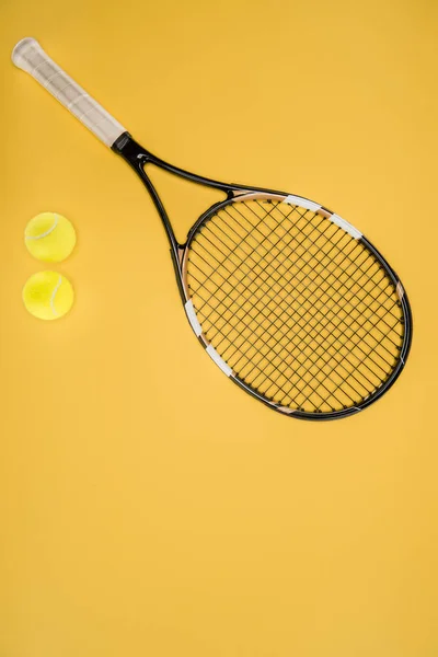 Tennis racket with balls isolated on yellow — Stock Photo