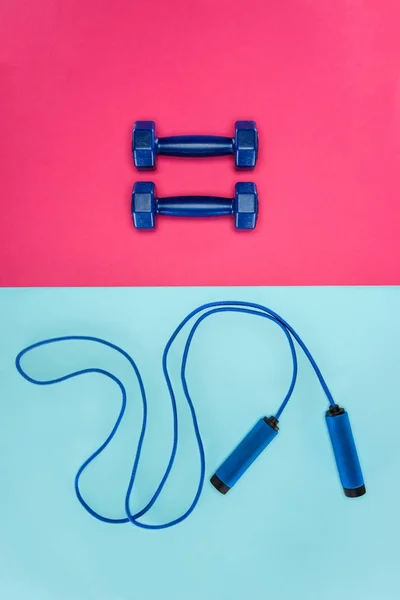 Manubri sportivi e corda da salto isolati su rosa e blu — Foto stock