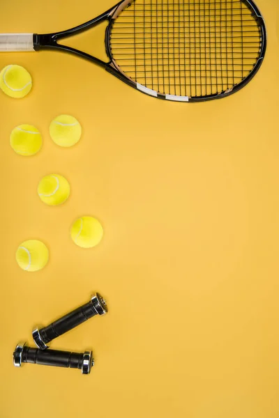 Black dumbbells and tennis racket with balls isolated on yellow — Stock Photo