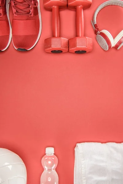 Спортивне обладнання з взуттям, гантелями, м'ячем та навушниками ізольовано на червоному — стокове фото