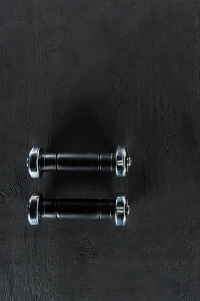 Black shiny dumbbells on black background — Stock Photo