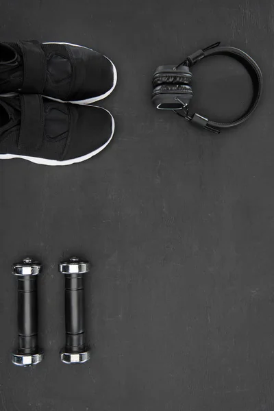 Sneakers, dumbbells and headphones on black background — Stock Photo