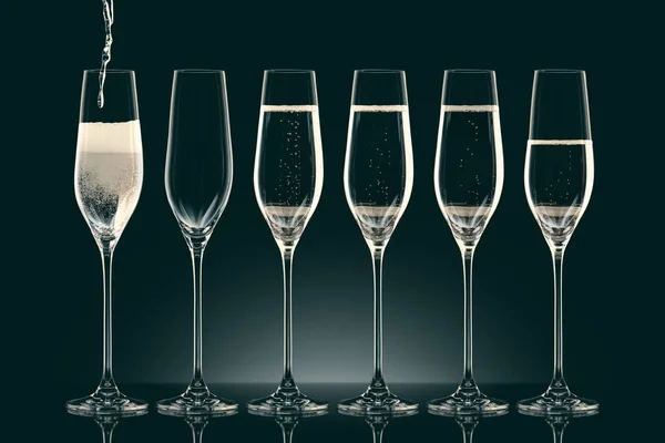 Pouring champagne into six transparent glasses on black — Stock Photo