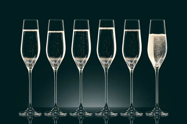 Six transparent glasses with champagne on black — Stock Photo