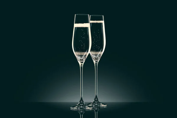Two transparent glasses of champagne on black — Stock Photo