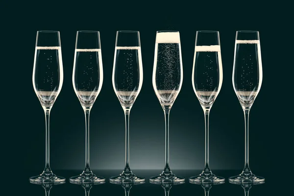 Six transparent glasses with champagne on black — Stock Photo