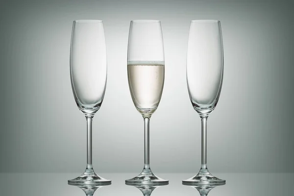 Dos vasos vacíos y una copa con champán sobre blanco - foto de stock