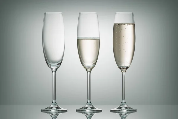 Tres copas con diferente nivel de champán en blanco - foto de stock