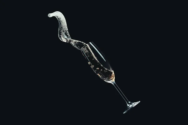 Spilling champagne from falling glass isolated on black — Stock Photo