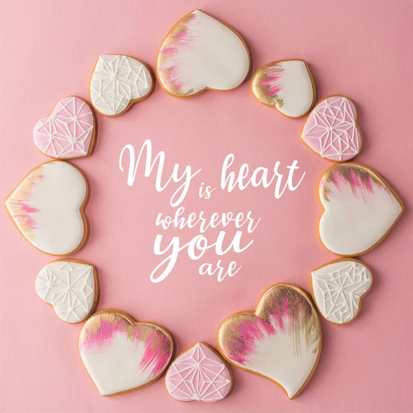 Flat lay with arrangement of glazed heart shaped cookies isolated on pink surface — Stock Photo