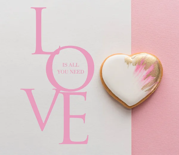 Vista superior de la galleta esmaltada en forma de corazón en la superficie rosa - foto de stock