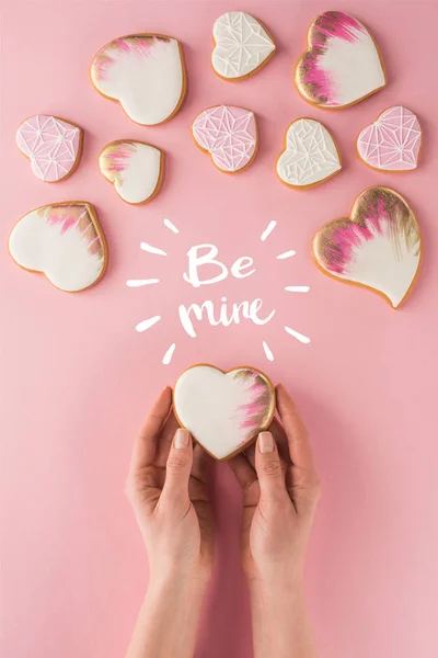 Partial view of woman holding glazed cookie in hands isolated on pink, st valentines day concept — Stock Photo