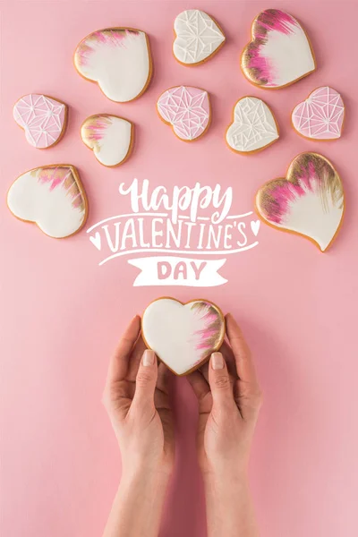 Visión parcial de la mujer sosteniendo galleta acristalada en las manos aisladas en rosa, San Valentín concepto de día - foto de stock