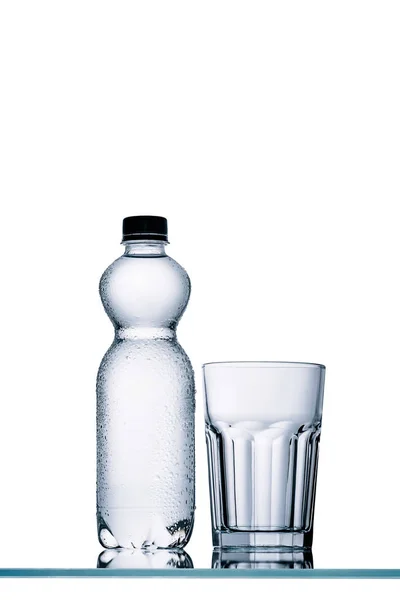 Volle Plastikflasche Wasser und leeres Glas isoliert auf weiß — Stockfoto